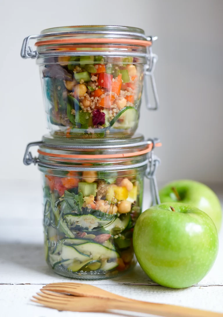 meal prep salad jars, stacked, next to two green apples and reusable utensils