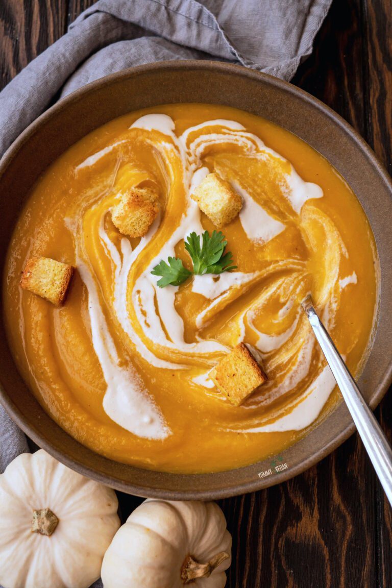 A bowl of Spiced Butternut Squash Soup topped with cashew cream, cilantro, and croutons (overhead shot)