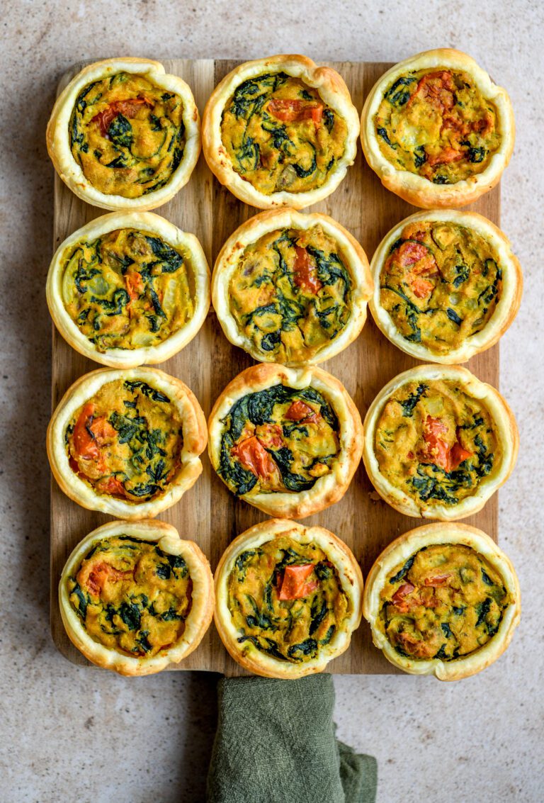12 mini quiches on a wooden board with a green cloth napkin
